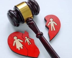 Le marteau d'un juge repose à côté d'un cœur rouge brisé avec des figures masculines et féminines, symbolisant une séparation