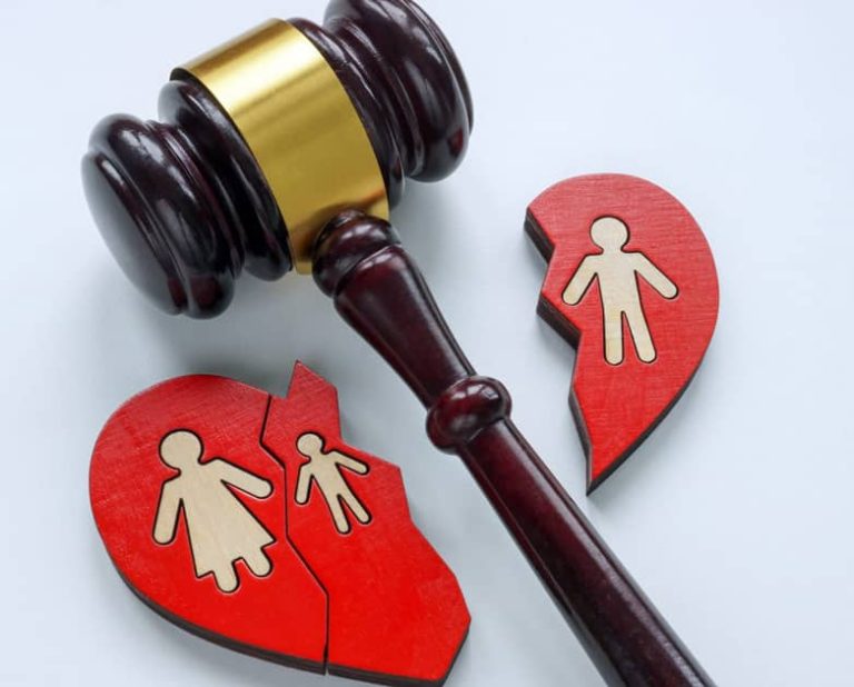 Le marteau d'un juge repose à côté d'un cœur rouge brisé avec des figures masculines et féminines, symbolisant une séparation