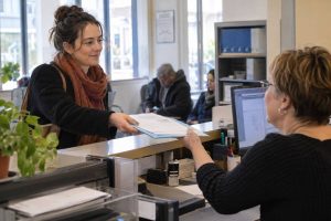 Une femme, à l'accueil, remet des documents à une réceptionniste
