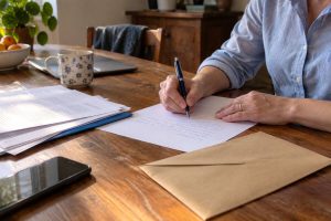 Une personne en train d'écrire une lettre à une table en bois
